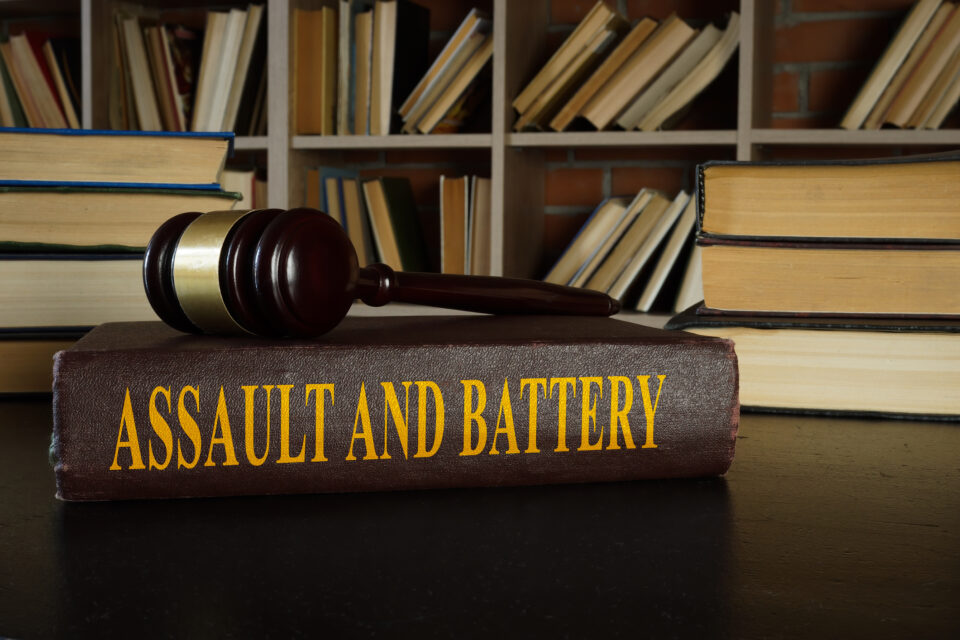 Law book titled 'Assault and Battery' with a gavel on top, set in a law library at Roberts Legal Services.
