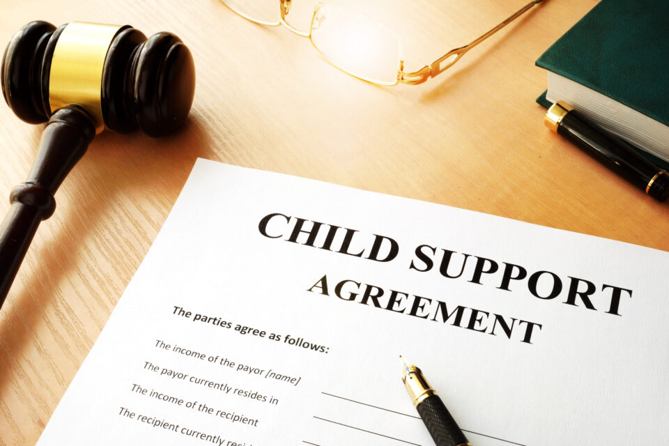 Child support agreement document with gavel, pen, and eyeglasses on a wooden desk, representing legal services for failure to pay child support