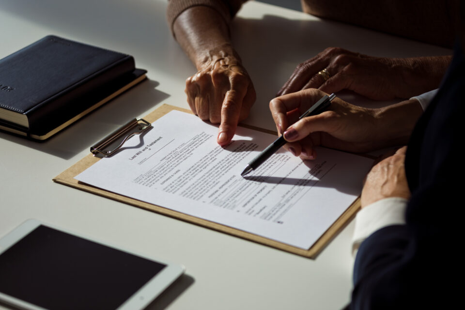 Close-up of a Last Will and Testament document being reviewed by an elderly individual and a legal professional