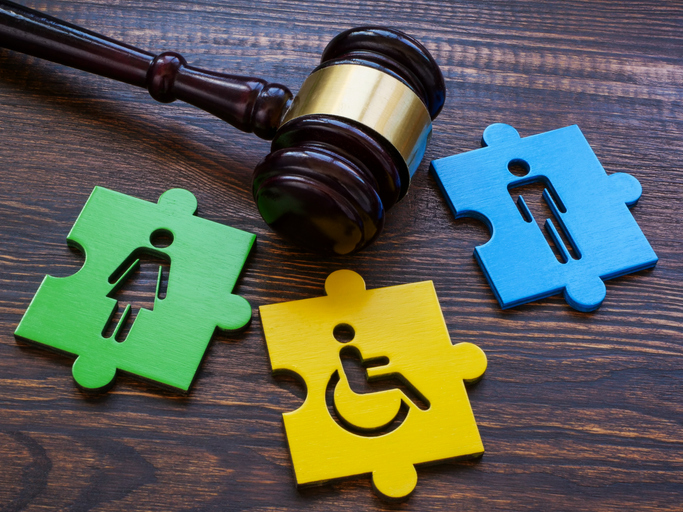 Judge's gavel on a wooden surface with colorful puzzle pieces symbolizing gender and disability inclusion, representing legal advocacy against employment discrimination.