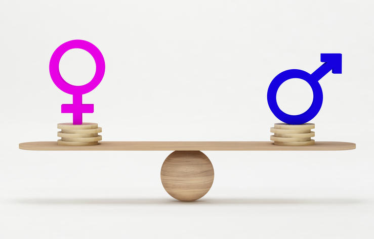 Balanced scale with male and female gender symbols on equal stacks of wooden discs, symbolizing equality and addressing sexual discrimination in the workplace.